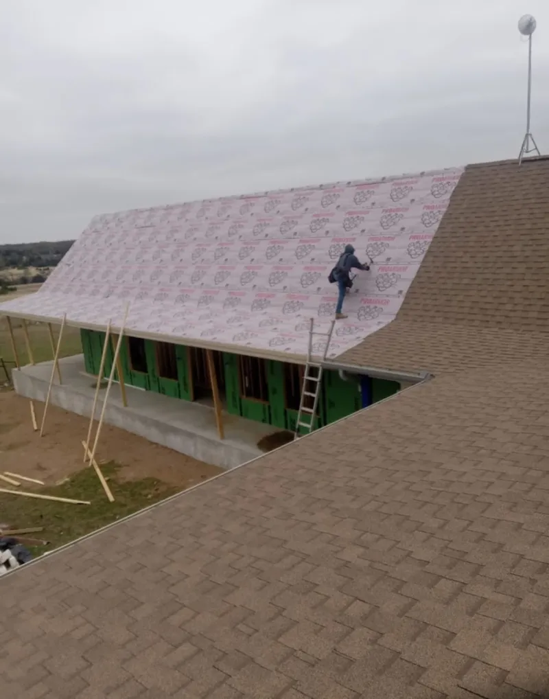 Worker preparing underlayment for a metal roof installation in Laredo